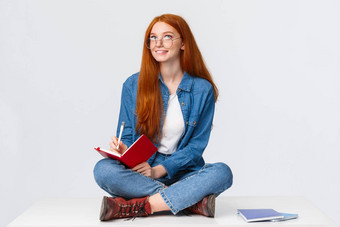 梦幻有创意的可爱的勤奋的女学生红色的头发眼镜坐着地板上腿交叉包围笔记本电脑写作创建诗深思熟虑的