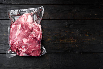 新鲜的有机肉羊肉羊肉真空包装黑色的木表格背景前视图平躺复制空间文本