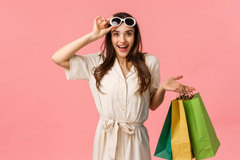 优秀的折扣季节有吸引力的年轻的浅黑肤色的女人衣服持有购物袋除去眼镜微笑价格站粉红色的背景
