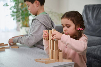 有创意的孩子们欧洲男孩女孩玩游戏叠加木玩具块高建筑结构手运动控制浓度技能教育休闲董事会游戏概念