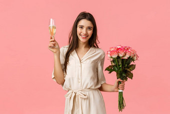 庆祝活动欢呼美概念美丽的年轻的温柔的女衣服持有花束花提高玻璃香槟给烤面包微笑享受聚会，派对粉红色的背景