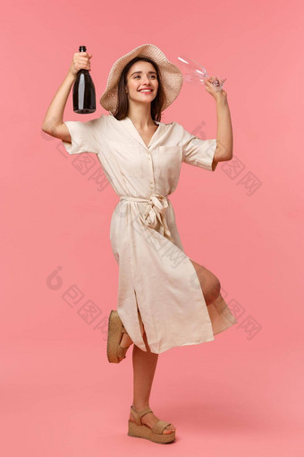 全身的垂直肖像快乐有魅力的年轻的女人他衣服跳舞提高了瓶香槟衣服笑享受庆祝场合站粉红色的背景