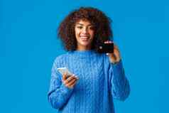 可爱的很高兴非裔美国人女银行客户推荐信贷卡银行系统服务持有智能手机微笑购买在线购物互联网商店蓝色的背景