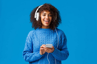 无忧无虑的快乐非裔美国人赶时髦的人女孩非洲式发型发型把耳机刺激最喜欢的跟踪享受太棒了声音质量耳机听音乐持有智能手机