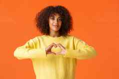 爱有爱心的温柔的可爱的浪漫的非裔美国人女表达感情显示心手势承认爱情人节一天站橙色背景快乐