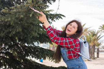 人假期庆祝活动概念年轻的女人装修圣诞节树在户外