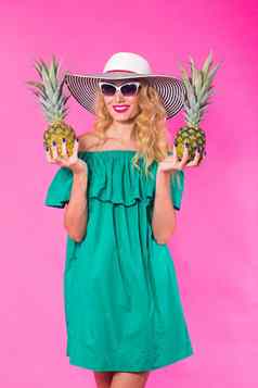 快乐年轻的女人持有菠萝粉红色的背景夏天饮食假期概念