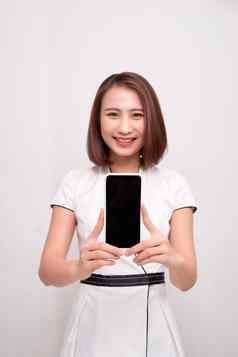 美丽的亚洲女人持有空白屏幕智能手机白色背景