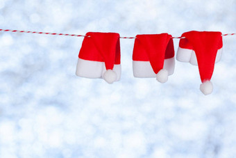 红色的圣诞节帽子挂绳子模糊闪亮的<strong>蓝灰色背景</strong>复制空间概念