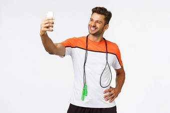 健康的生活方式体育运动人概念英俊的快乐微笑肌肉发达的男人。促进活跃的休闲采取自拍智能手机咧着嘴笑骄傲耐力锻炼健身房培训跳绳子