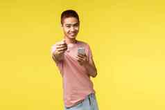 技术沟通生活方式概念肖像年轻的时尚的亚洲的家伙给无线耳机分享耳机听音乐持有移动电话