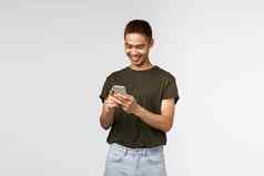 技术在线生活方式沟通概念肖像好看的亚洲年轻的的家伙绿色t恤快乐的移动电话发短信微笑智能手机屏幕