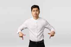 持怀疑态度傲慢的亚洲商人白色衬衫裤子指出相机不满意不生闷气的扮鬼脸粗心的表达不喜欢嘲笑白色背景