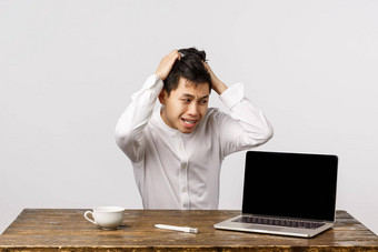 警觉恐慌中国人的家伙拉头发头坐着陷入困境的陷入困境的巨大的问题盯着移动PC焦虑紧张表达式坐着办公室白色背景