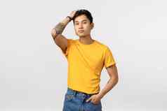 时尚的自信好看的中国人纹身的家伙黄色的t恤运行手指头发自信的相机爱站白色背景满意