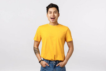 友好的快乐的逗乐好看的亚洲的家伙时尚的黄色的t恤牛仔裤持有手口袋微笑笑有趣的电影看单口显示站娱乐