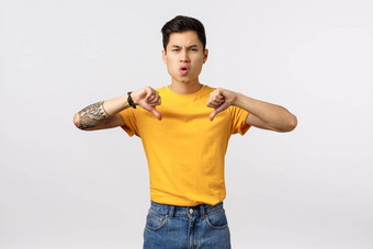 吸失望不高兴年轻的亚洲的家伙纹身黄色的t恤显示责备愤怒的脸<strong>鄙视</strong>不赞成坏游戏站白色背景心烦意乱