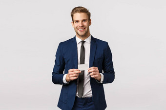 英俊的成功的年轻的商人经典蓝色的西装持有信贷卡微笑快乐促进银行在线购买系统订单产品铂卡显示机场工作人员