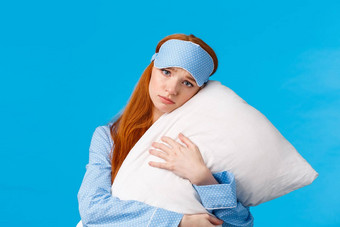 伤心红色头发的人女孩感觉抑郁不要大学说谎床上拥抱枕头皱着眉头不安有关紧张表达式穿睡眠面具睡衣蓝色的背景