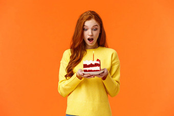 女孩使收到生日蛋糕蜡烛庆祝生日收到惊喜感觉逗乐感激的甜点钦佩快乐表达式橙色背景