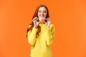 红色头发的人愚蠢的快乐华丽的女孩买美味的马卡龙持有食物欲望感情糖果吃站橙色背景满意快乐的