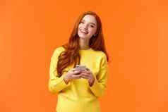 女孩搜索礼物假期在线无忧无虑的快乐红色头发的人女学生智能手机应用程序笑快乐持有移动电话聊天浏览社会网络橙色背景