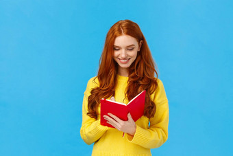 半身照肖像红色头发的人女学生写的想法红色的可爱的笔记本准备杂货店列表使时间表大学讲座微笑分享的想法日记蓝色的背景