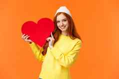 的关系的男朋友女朋友爱概念快乐的可爱的红色头发的人女孩持有大红色的心标志微笑表达感情显示的真实感受爱合作伙伴橙色背景