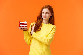 不要可爱的红色头发的人女孩抵制诱惑咬美味的糖果持有美味的蛋糕显示停止拒绝拒绝扮鬼脸脸表达厌恶不喜欢