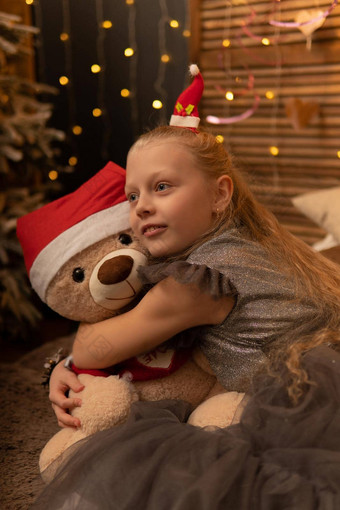 女孩拥抱熊玩具圣诞节帽熊圣诞节孩子女孩快乐女微笑泰迪白色有趣的快乐婴儿礼物床上持有拥抱之后