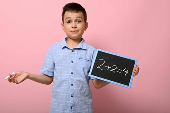 可爱的男孩小学学校学生持有粉笔黑板上解决了数学问题粉红色的背景空间文本回来学校概念