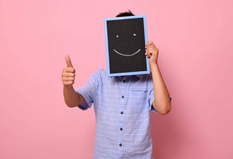 学校男孩涵盖了脸黑板画微笑表情符号表达幸福显示拇指相机孤立的粉红色的背景复制空间