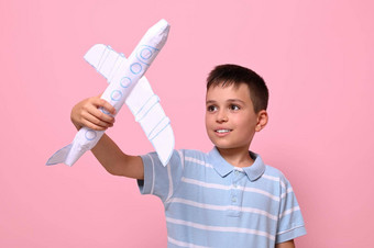 英俊的小学生玩纸飞机粉红色的背景复制空间旅游旅行地理位置知识概念