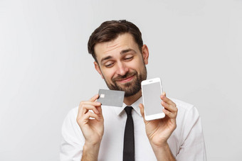 照片自信企业家男人。西装领带持有智能手机信贷卡支付在线孤立的灰色的背景