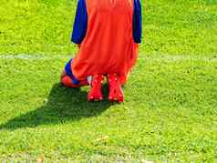 女孩红色的运动型泽西岛运动鞋坐着足球球场