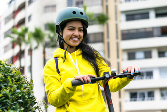 笑年轻的女人头盔电踏板车
