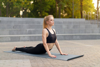 健身女人实践瑜伽练习席户外城市街阳光背景