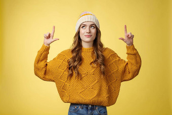 有吸引力的梦幻时尚的大学女孩穿他温暖的毛衣指出前微笑很高兴找到好奇的很酷的促销推荐提供广告复制空间黄色的背景