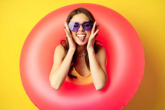 关闭肖像热情的年轻的女人内部粉红色的游泳环笑微笑享受海滩假期夏天假期黄色的背景