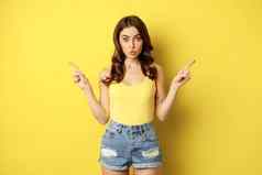 肖像时尚的年轻的女模型显示广告指出标志横幅展示方法选择商店站黄色的背景