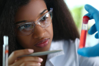 非洲美国化学家持有玻璃测试管红色的液体解决方案