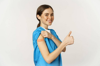 微笑护士医生实习医生风云医疗工人显示接种疫苗肩膀补丁拇指推荐接种疫苗冠状病毒白色背景