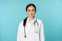 医疗工作人员医生概念年轻的微笑女医生医疗保健工人白色外套听诊器自信等待病人蓝色的背景