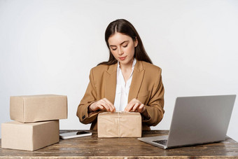 年轻的女商人自由职业者女人坐着办公室移动PC包装<strong>包包</strong>装客户订单工作白色背景