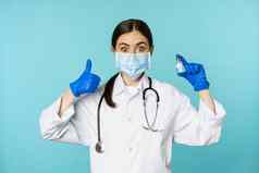 肖像微笑医生医疗personel脸医疗面具橡胶手套显示拇指冠状病毒ο疫苗站蓝色的背景