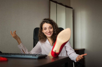 portriat浅黑肤色的女人腿办公室表格移动PC热女人红色的鞋子高高跟鞋坐着桌子上概念诱人的秘书女时尚放松工作