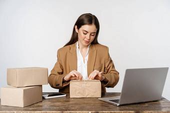 启动企业家概念年轻的女商人自由职业者女人包装包包装客户订单坐着移动PC工作白色背景