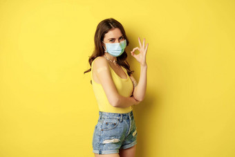 肖像年轻的女人接种疫苗科维德流感穿脸面具显示<strong>标志推荐</strong>拍摄女孩补丁肩膀疫苗接种站黄色的背景