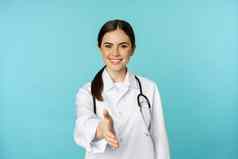 微笑专业女人医生治疗师扩展手握手手势问候病人医疗诊所医院站蓝色的背景