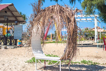 真正的自然美背景沙子海滩公园的地方浪漫的放松时间白色木轮板凳上干棕榈叶子阴影米色树冠绿松石蓝色的天空不寻常的时尚的现代户外家具